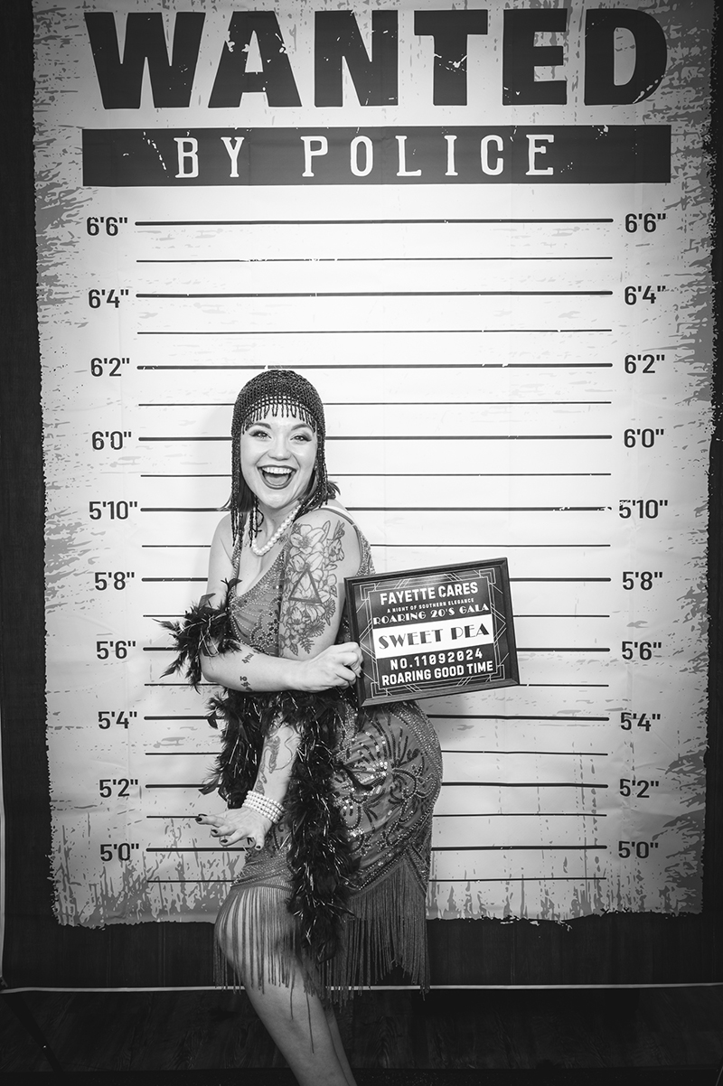 Woman posing in front of wanted poster backdrop